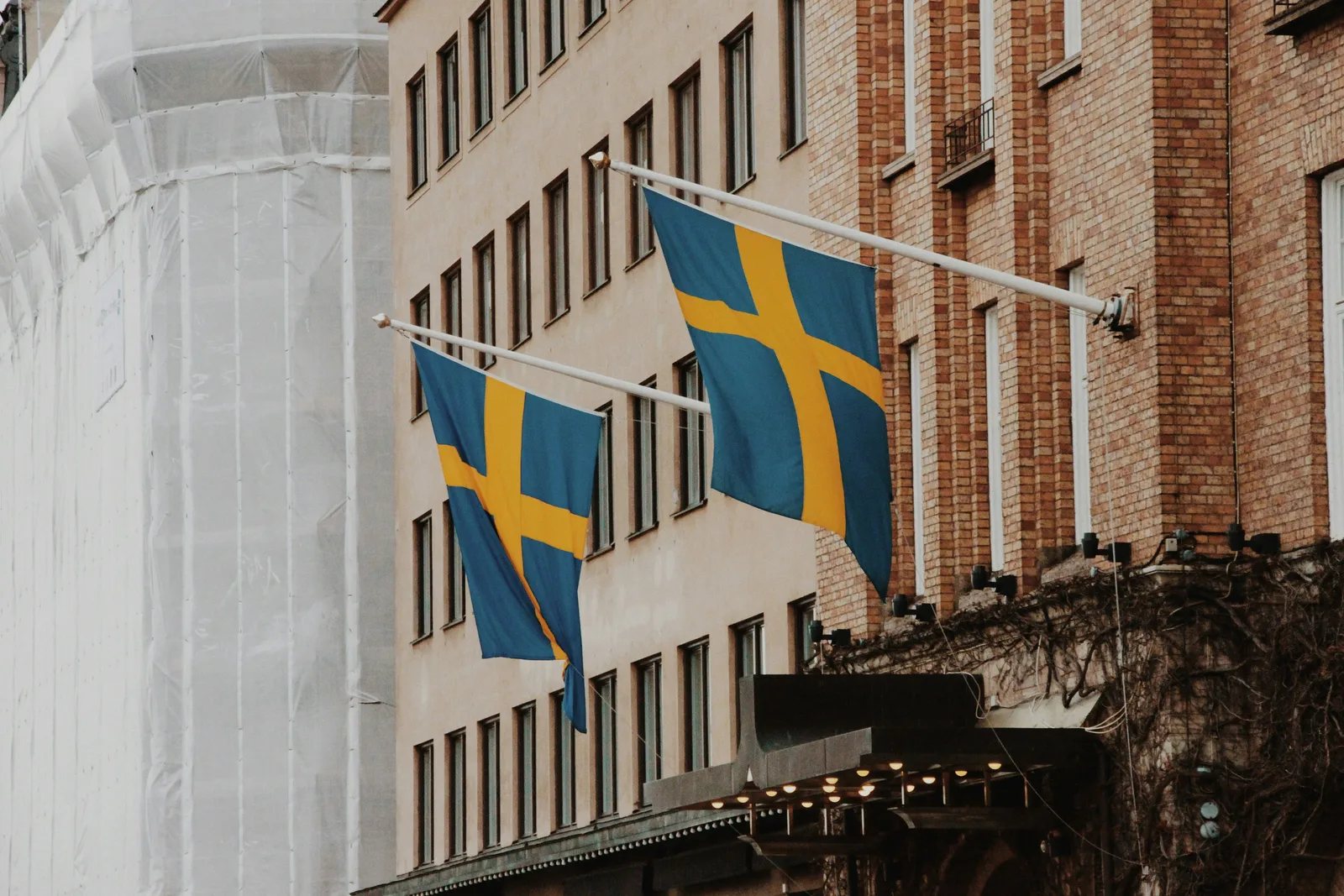 Svenska flaggor framför en modern fastighetsfasad.